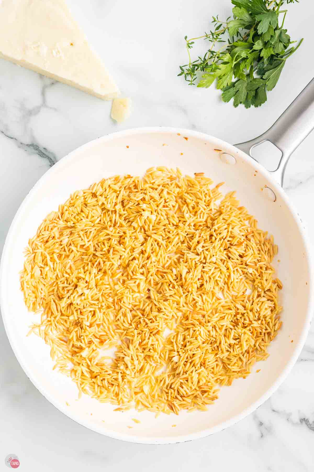 toasted orzo pasta in a white skillet