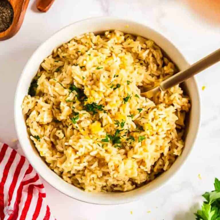 bowl of rice tossed with lemon and pesto with a large spoon in it