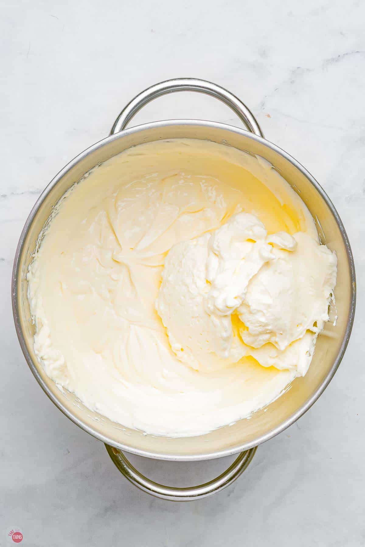 cream cheese and sugar being whipped in a mixing bowl