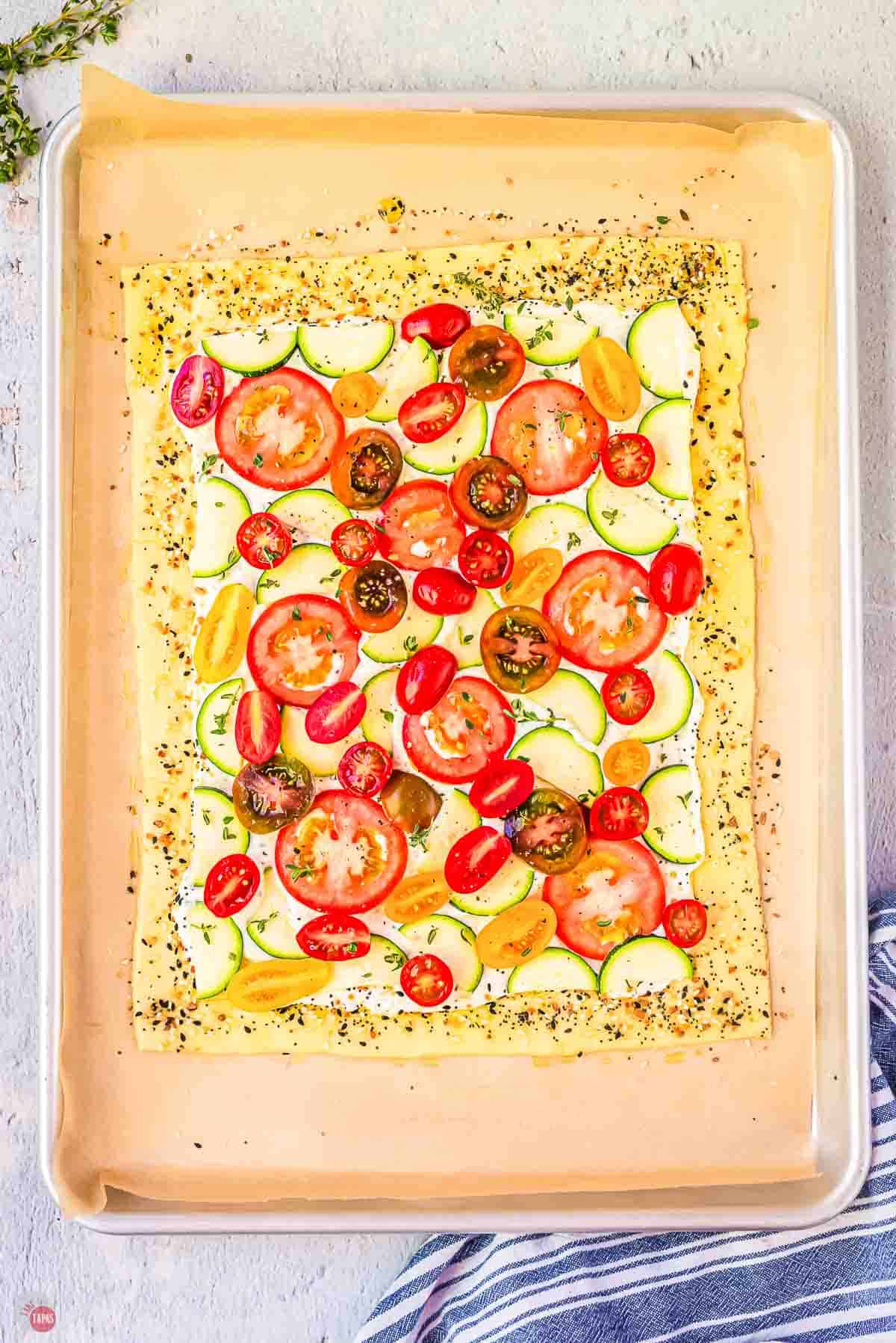 fresh slices of tomato and zucchini on a piece of parchment paper