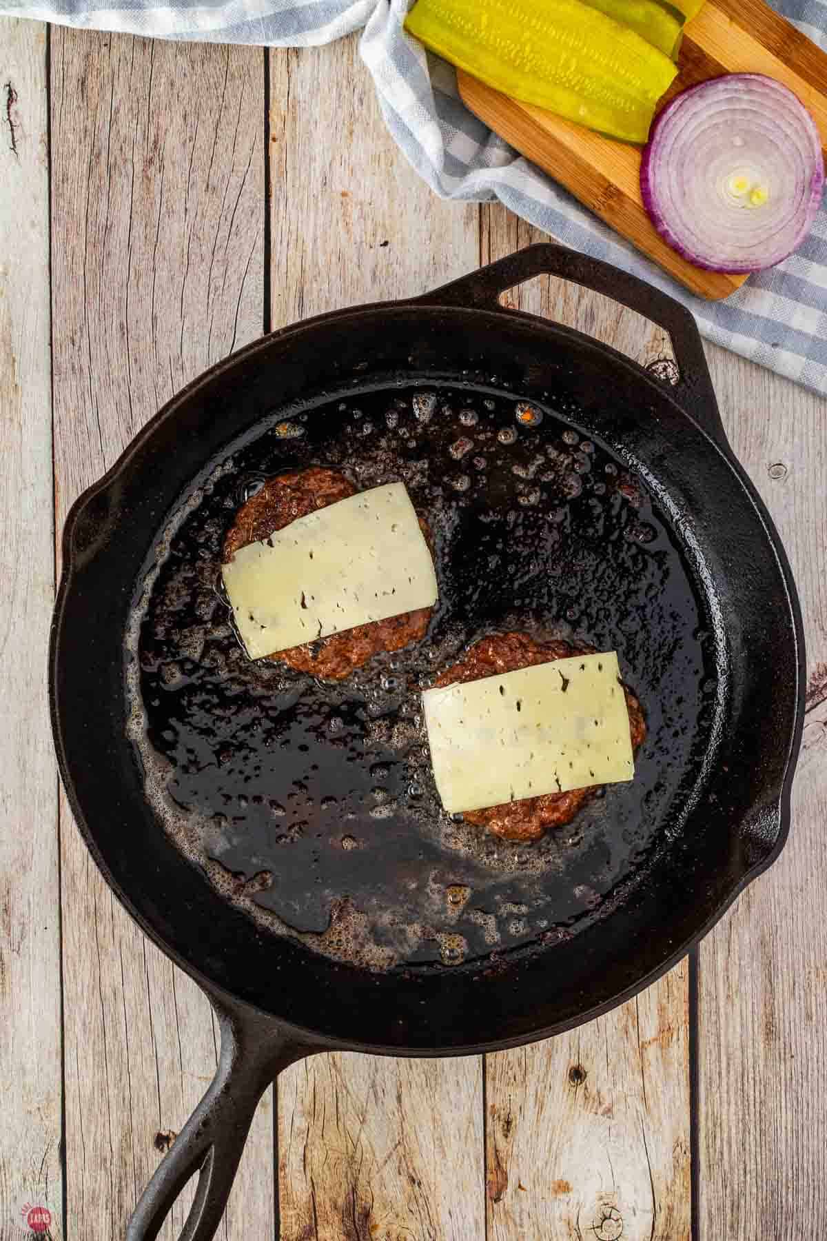 two burgers topped with pieces of cheese