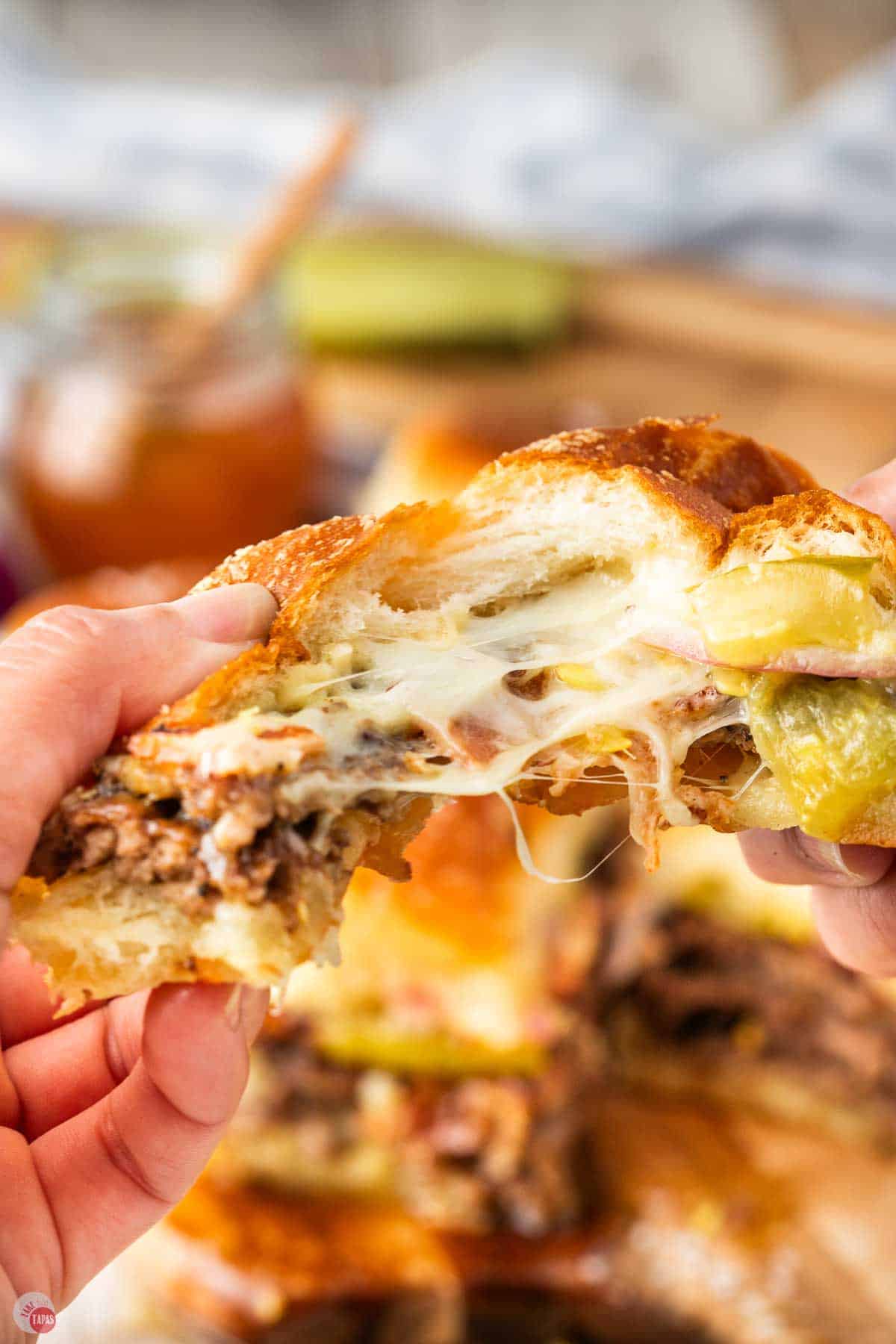 two hands pulling a smash burger slider apart