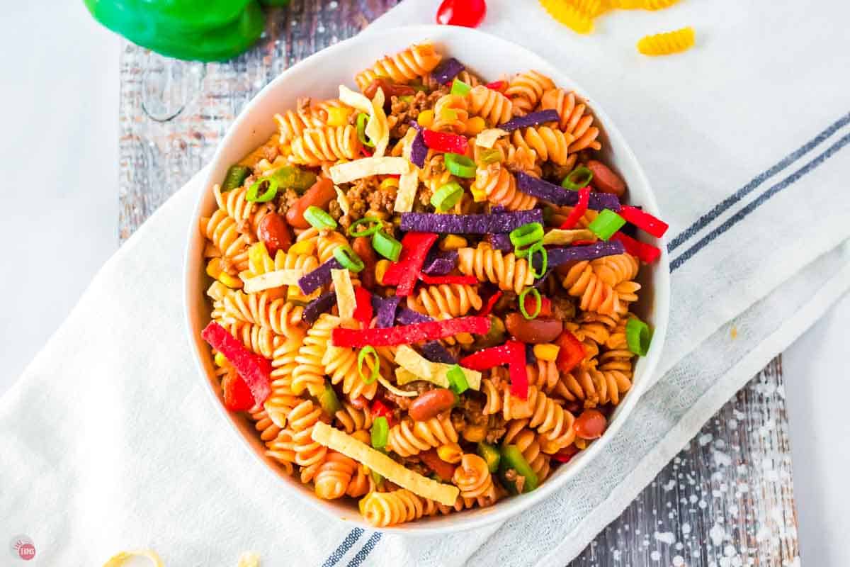 white bowl of taco pasta salad with colored tortilla strips