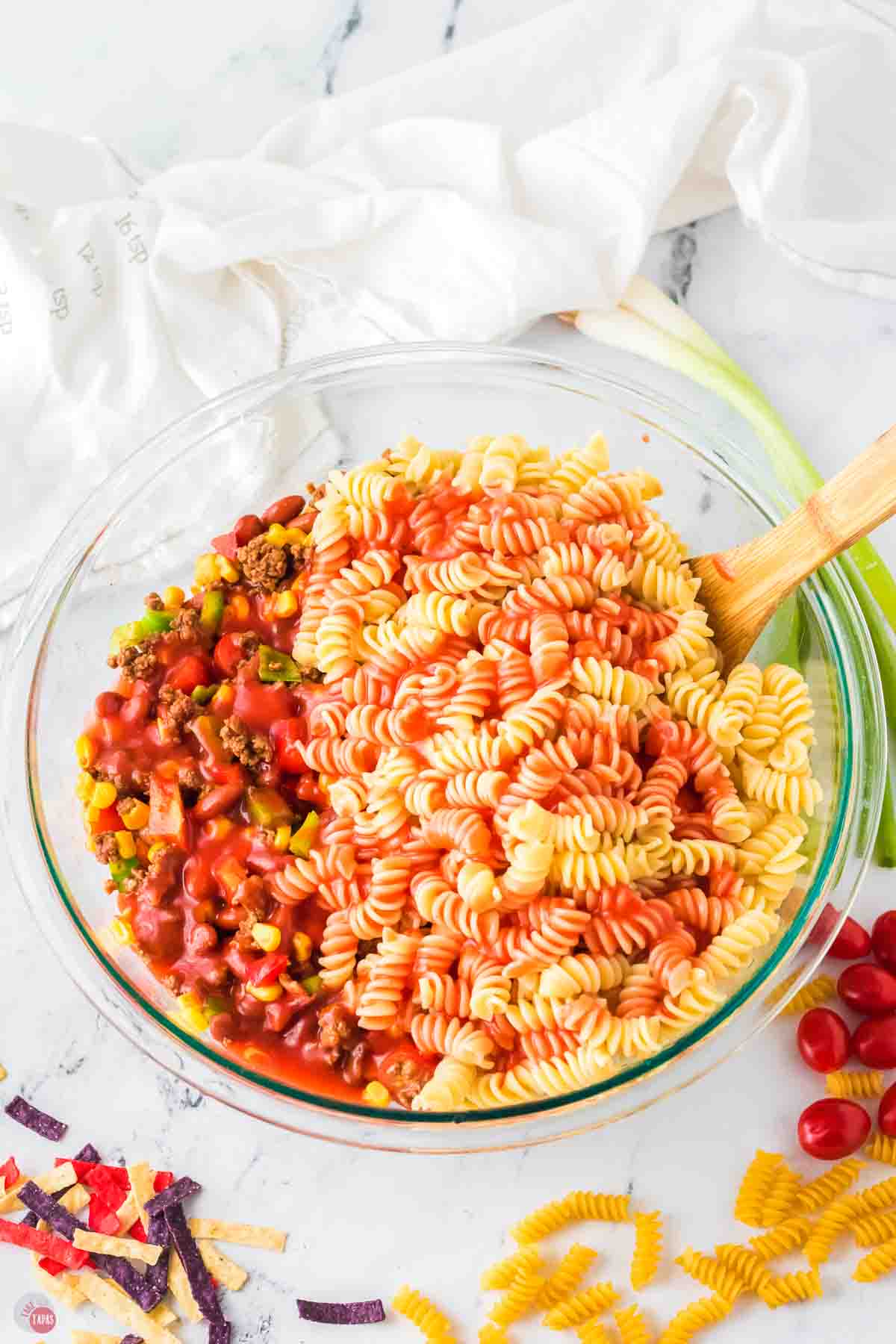 bowl of pasta salad being tossed in dressing