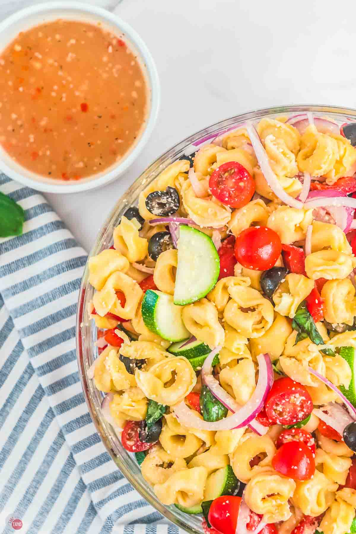 close up of fresh pasta salad with a bowl of dressing