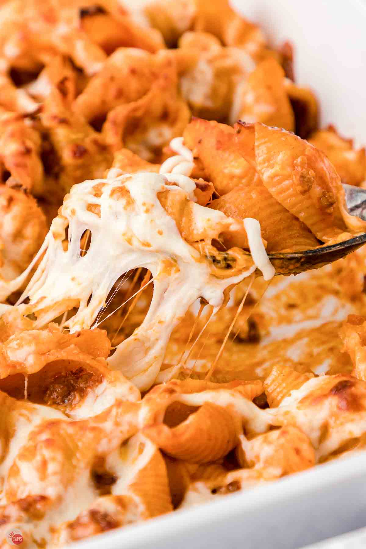 spoon scooping pasta and cheese out of a casserole dish