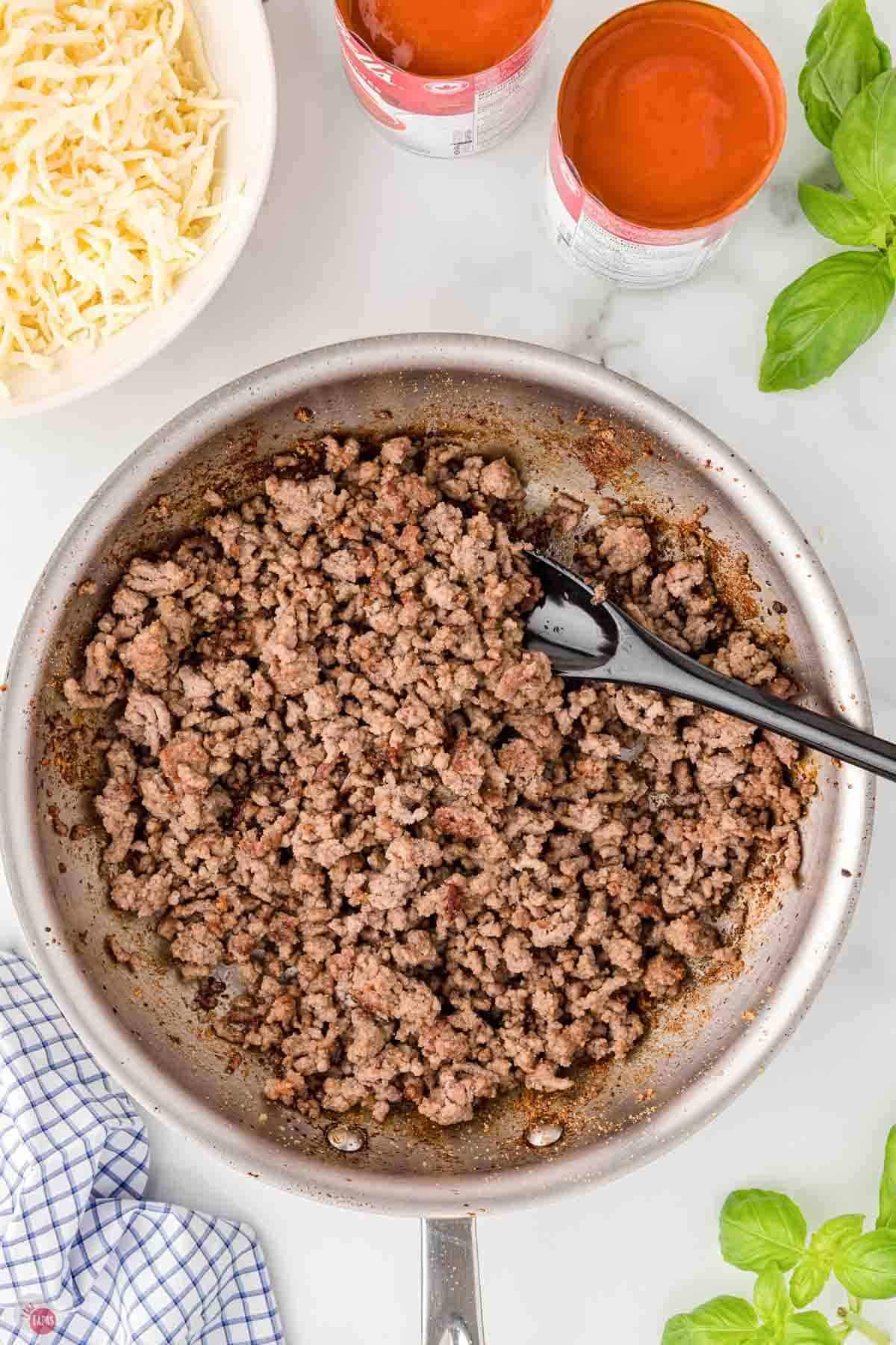 cooked ground beef in a skillet with a black spoon