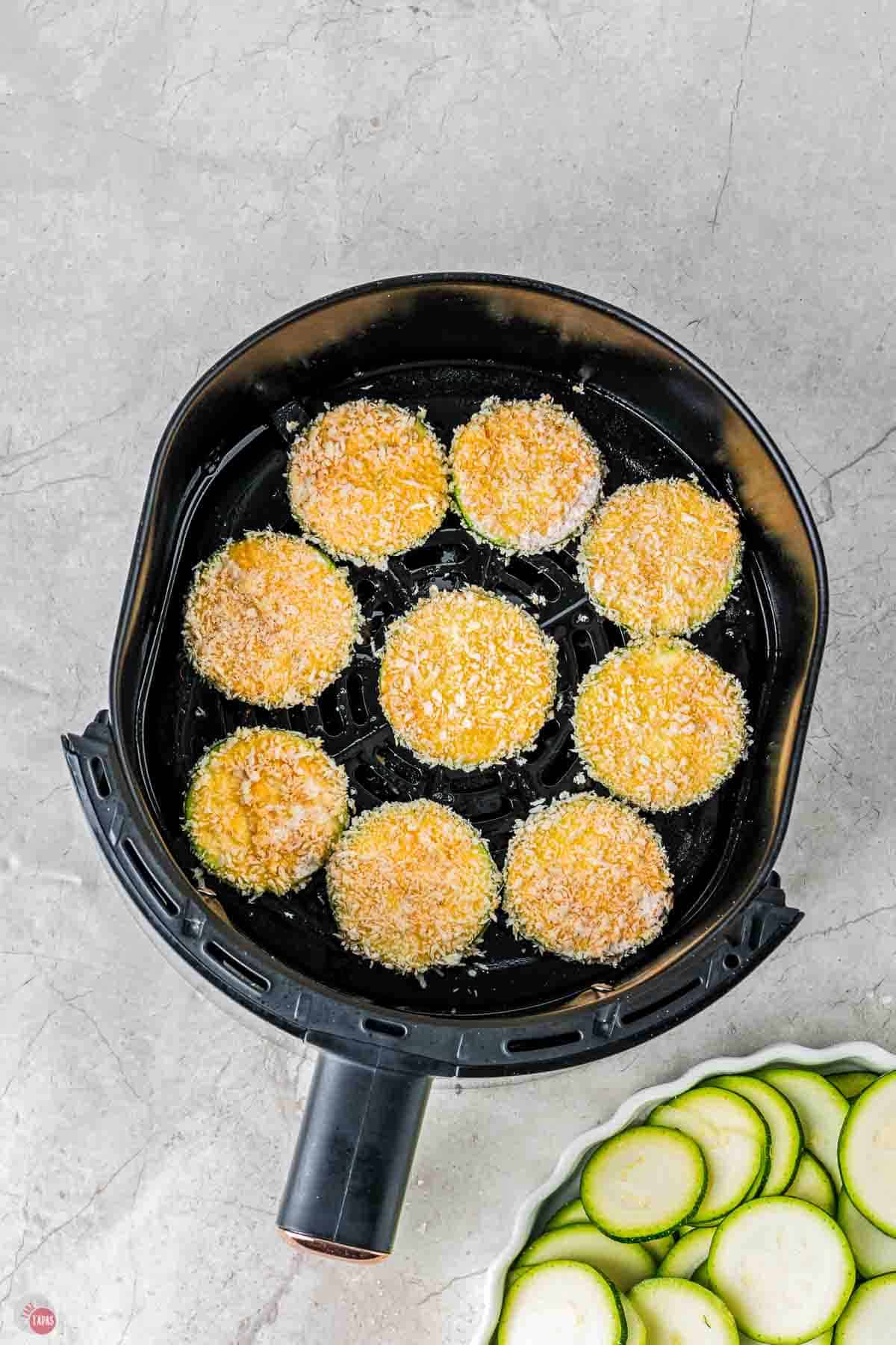 coated zucchini slices in an air fryer basket