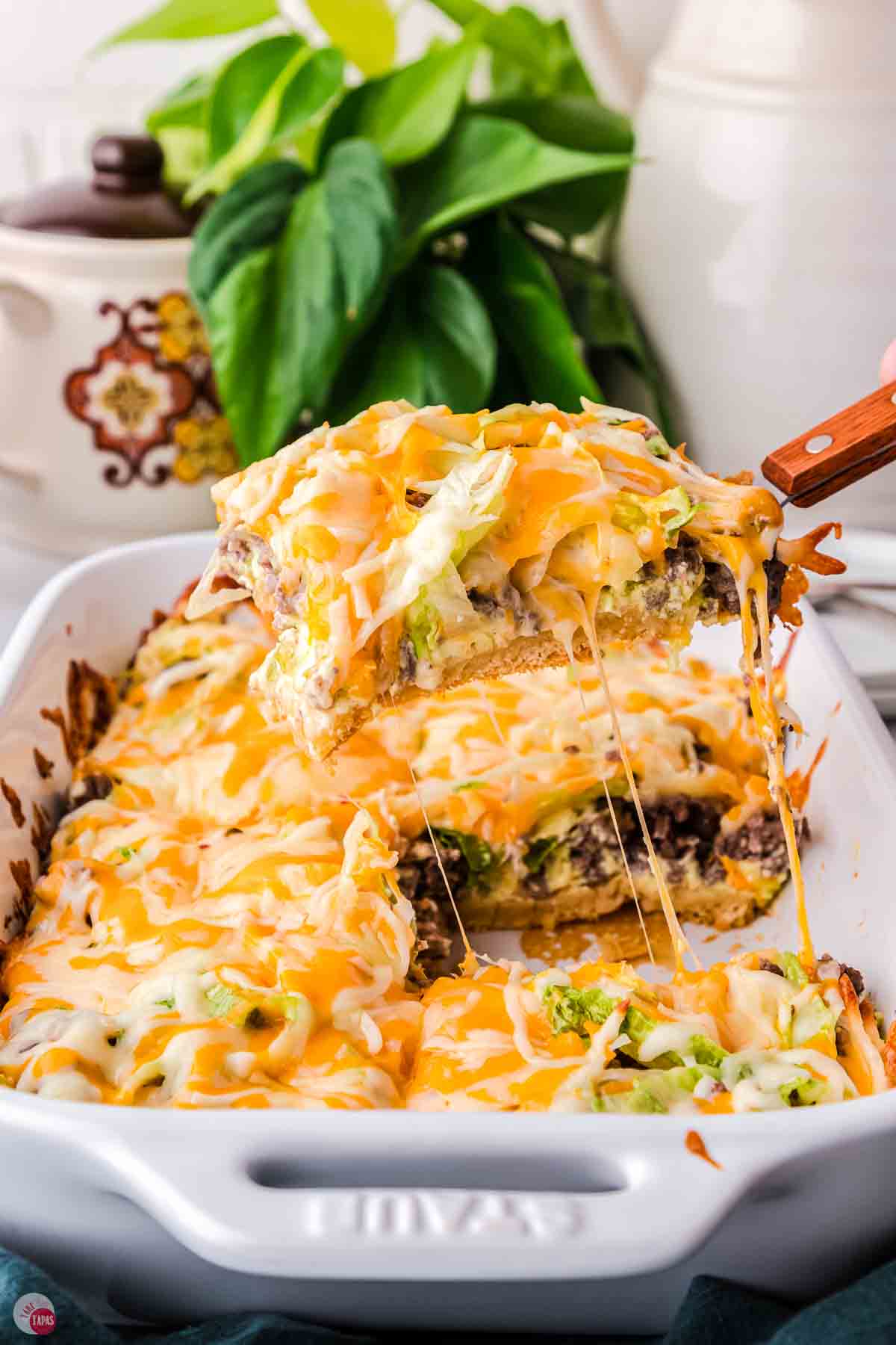 spatula scooping a big slice of cheesy casserole out of a dish