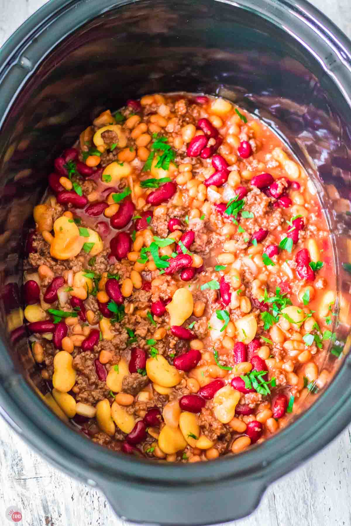 close up of slow cooker bowl full of beefy calico beans