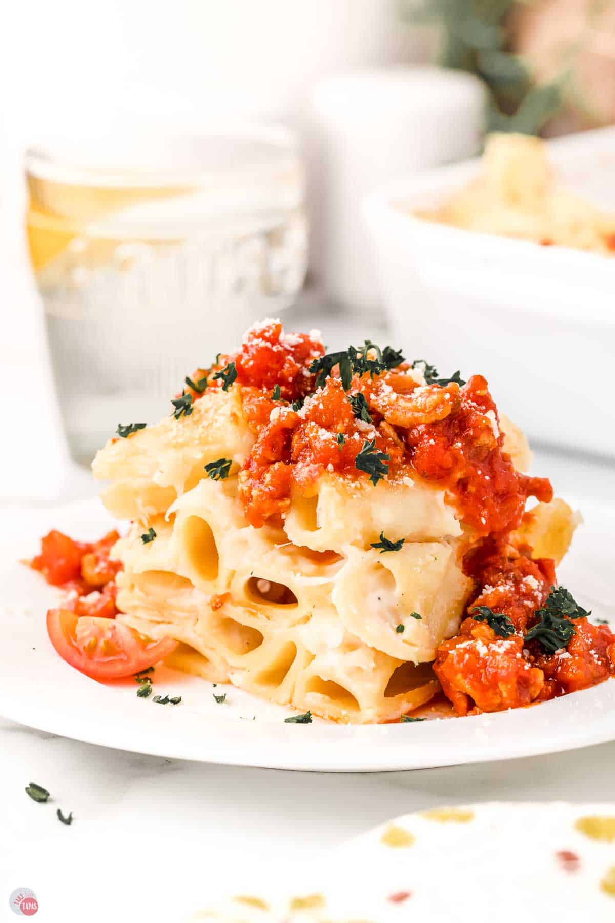 plate of cheesy rigatoni topped with a meat sauce and chopped parsley