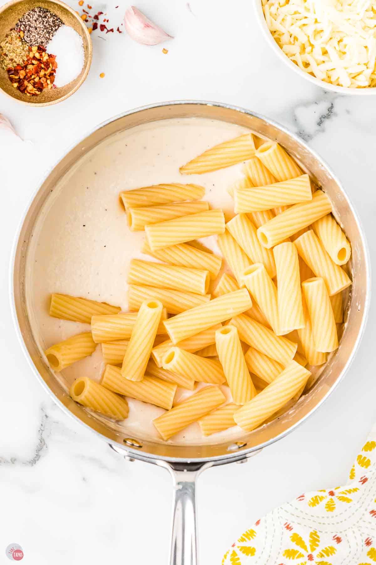 cooked pasta noodles and alfredo sauce in a sauce pan