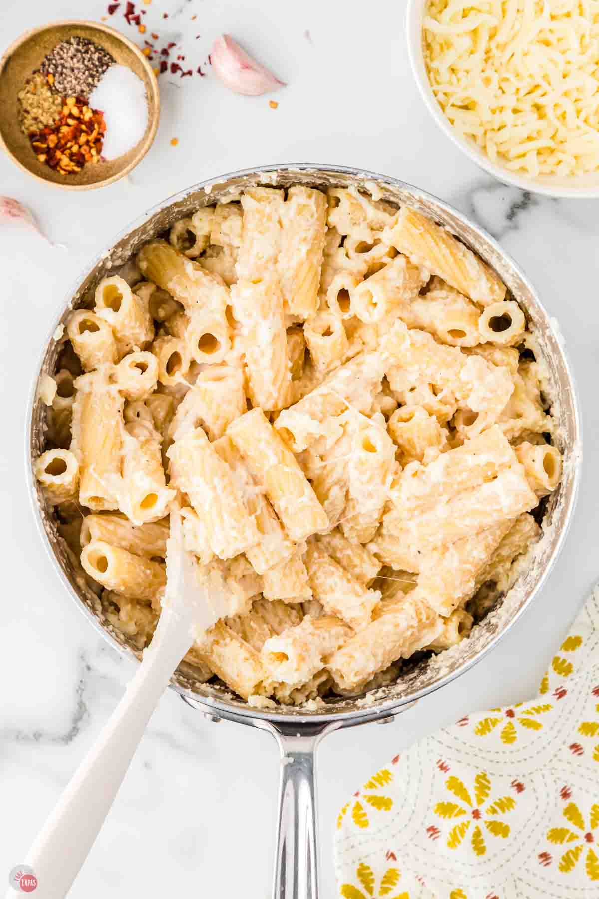 cheesy rigatoni noodles in a pot with alfredo sauce