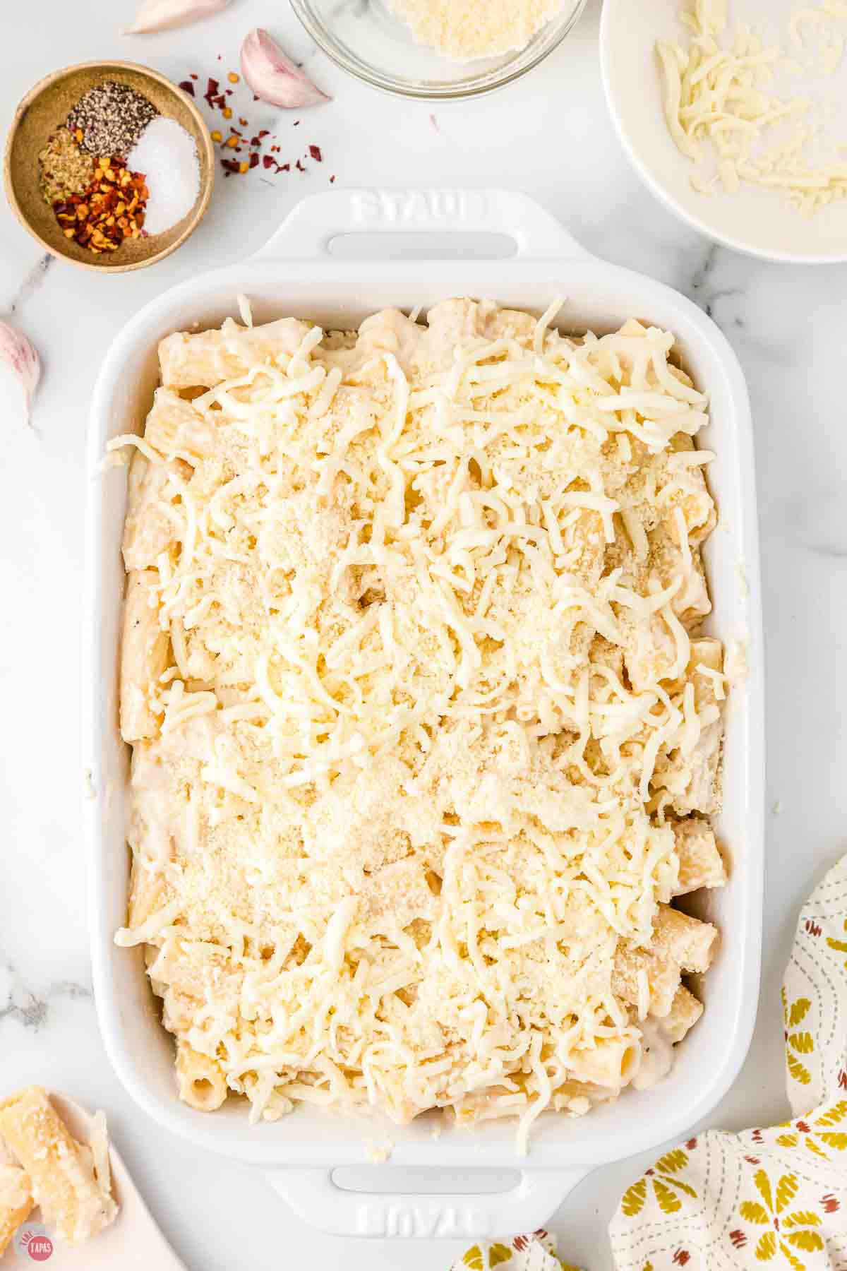 cheesy rigatoni baked in a casserole dish topped with shredded cheese