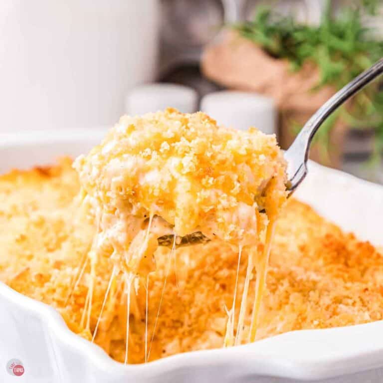 spoon scooping mac and cheese out of a white baking dish