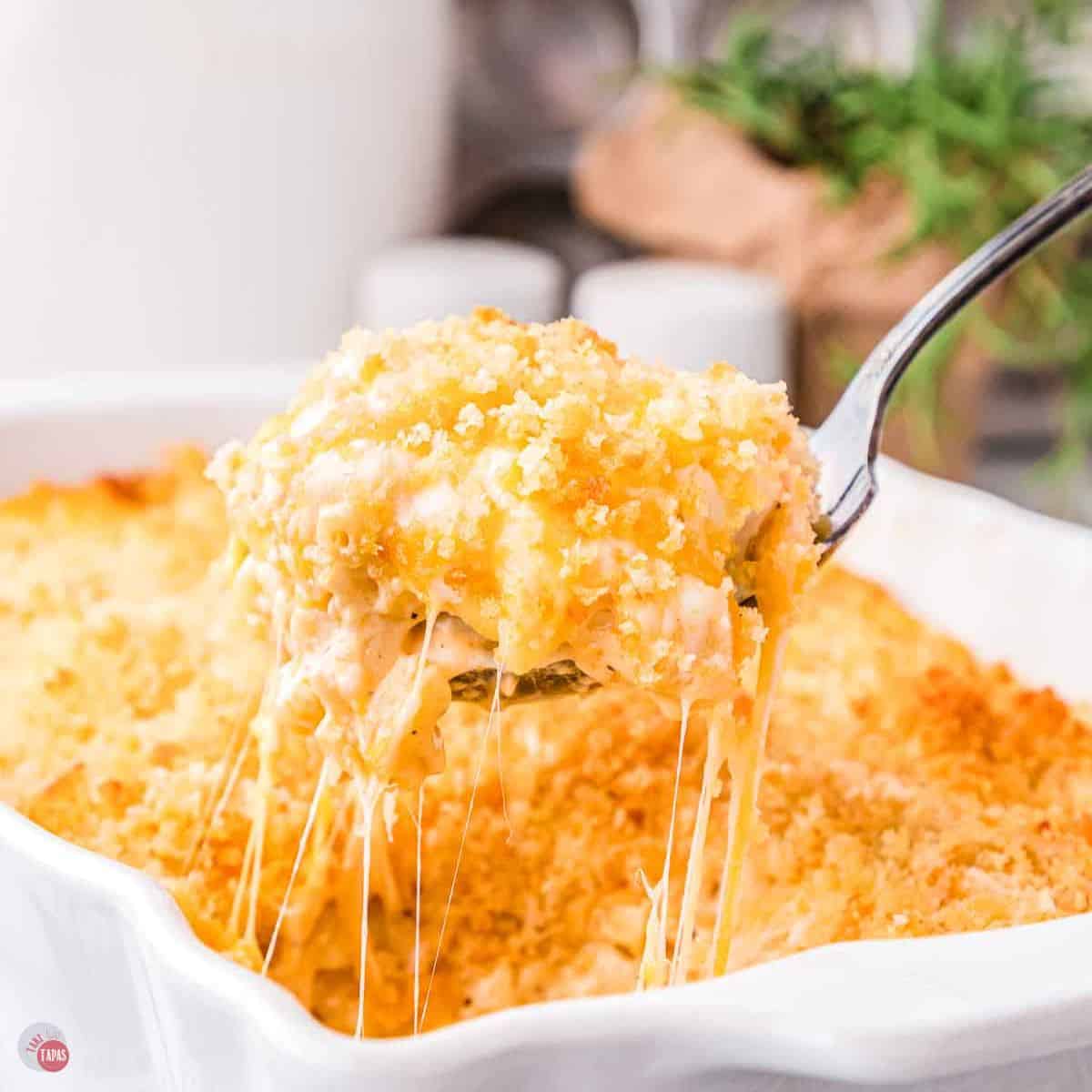 spoon scooping mac and cheese out of a white baking dish