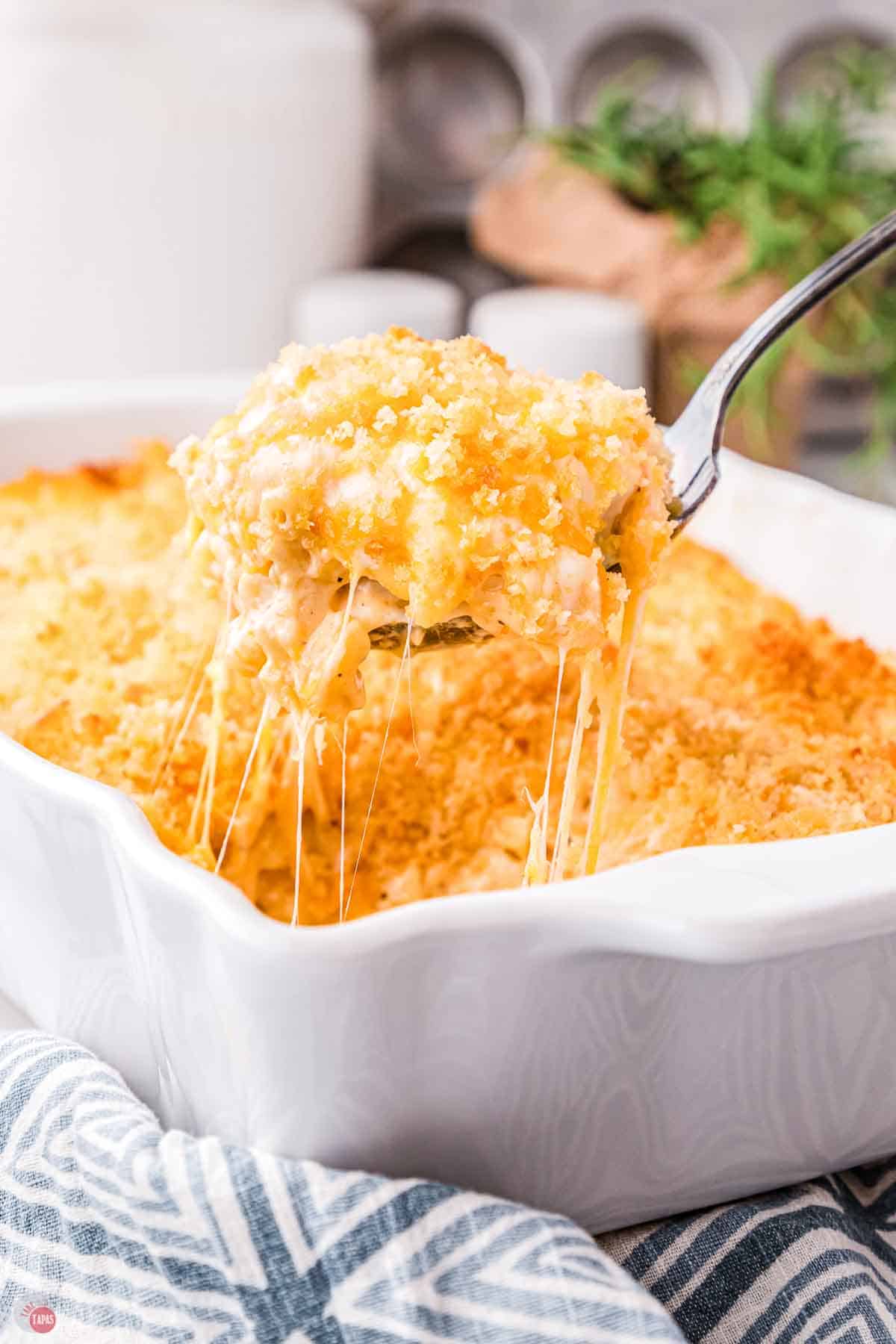spoon scooping mac and cheese out of a white baking dish