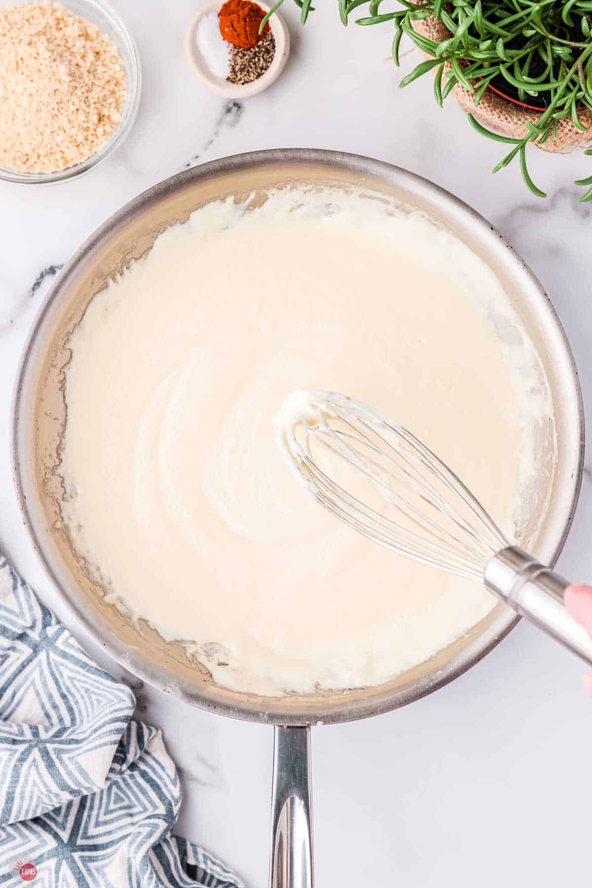 skillet with a cream sauce being whisked