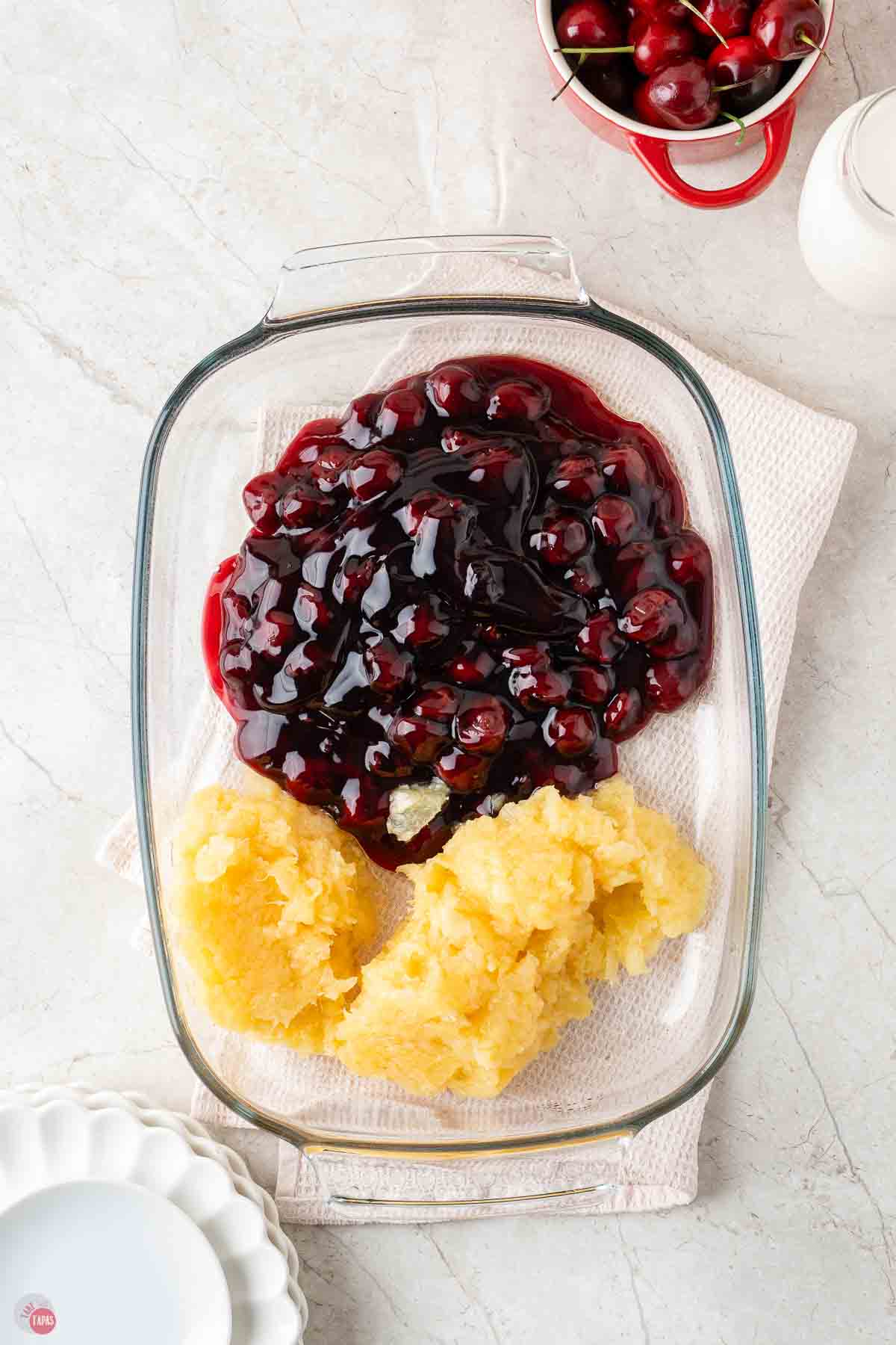 crushed pineapple and cherry pie filling in a clear baking dish