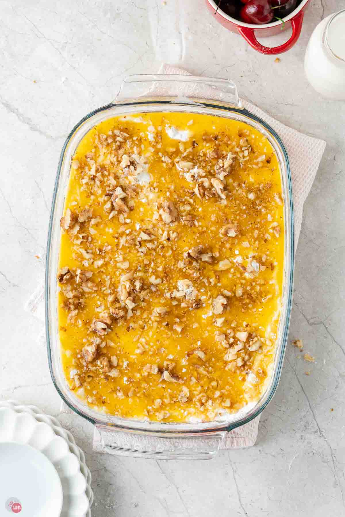 melted butter and walnuts on cake mix powder in a casserole dish
