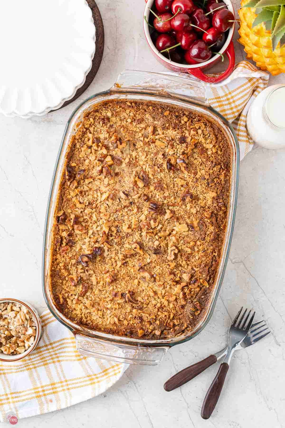 baked cherry dump cake next to forks and a stack of plates