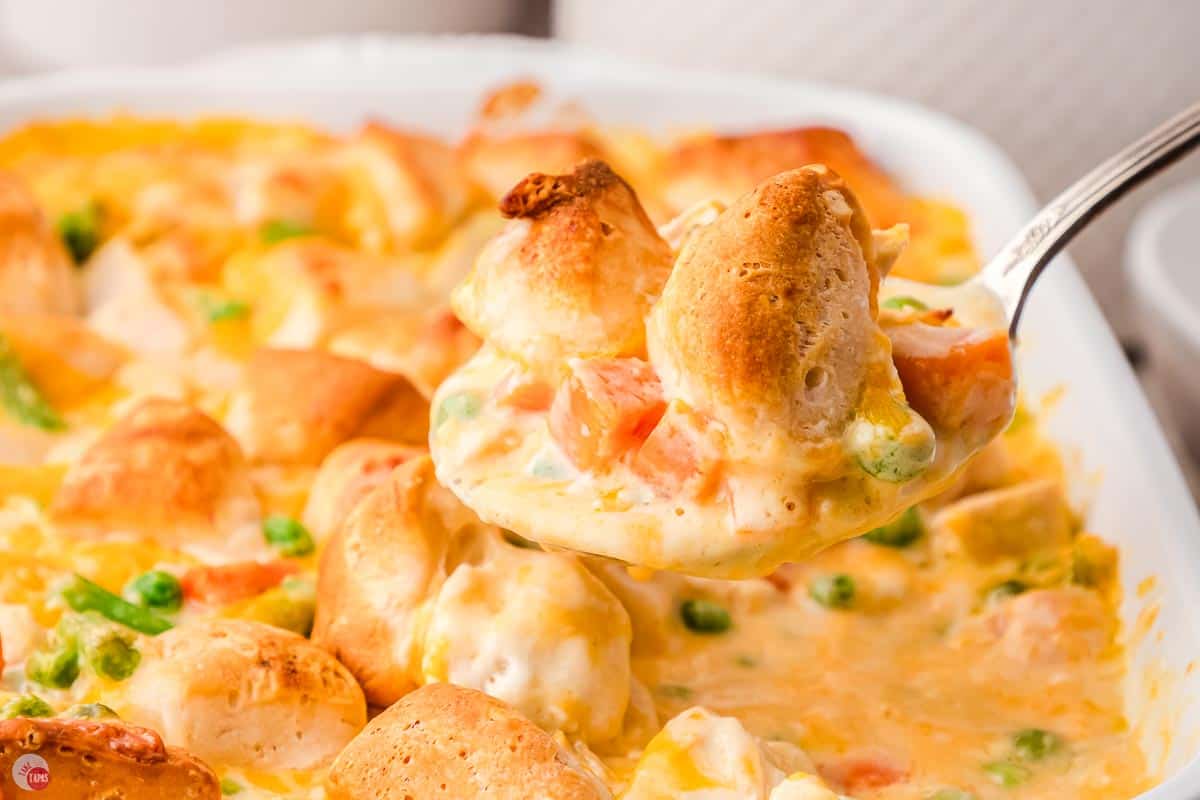 side view of a large spoon scooping chicken casserole out of a dish