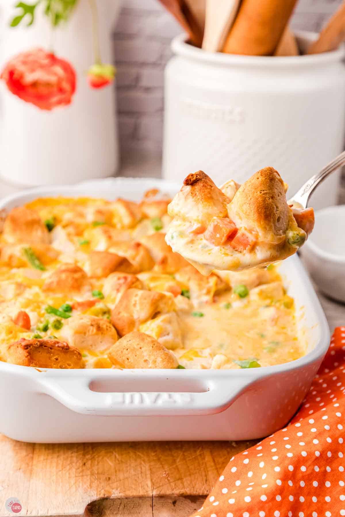 spoon scooping casserole out of a white baking dish