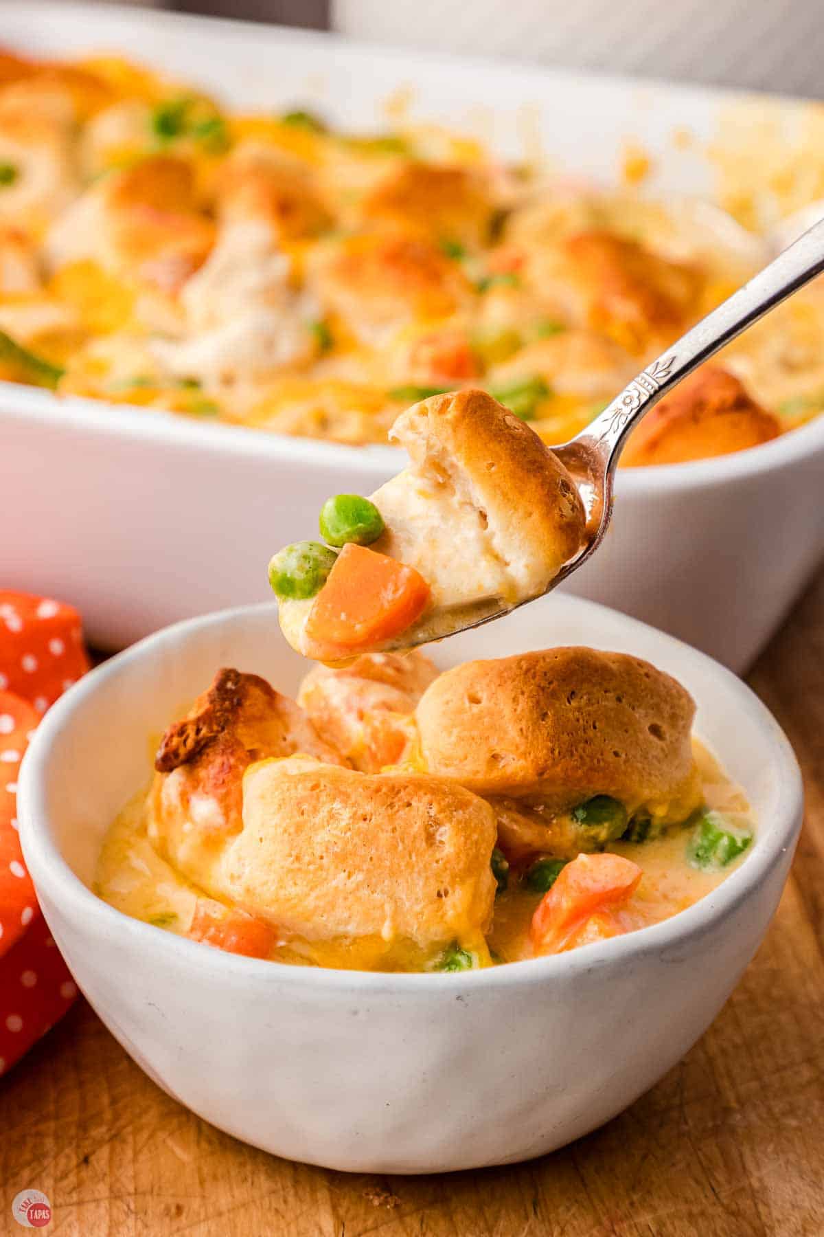 fork with bite of chicken, vegetables, and biscuits