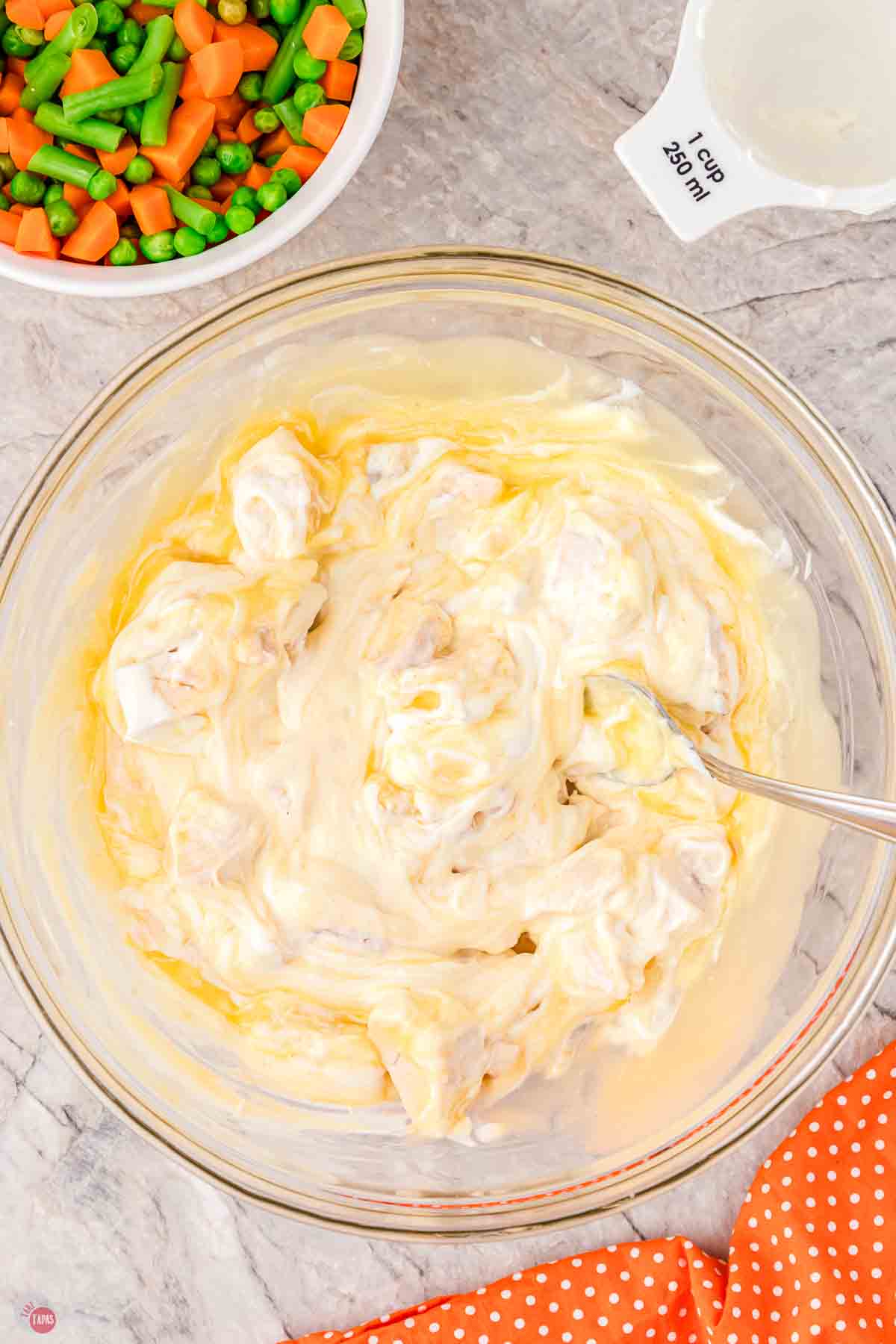 chicken, soup, and sour cream mixed in a clear bowl