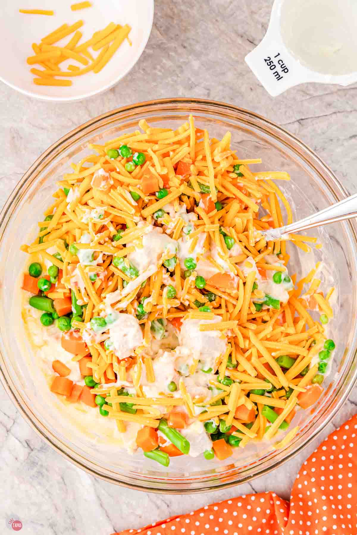 mixed vegetables and chicken being stirred in a clear bowl