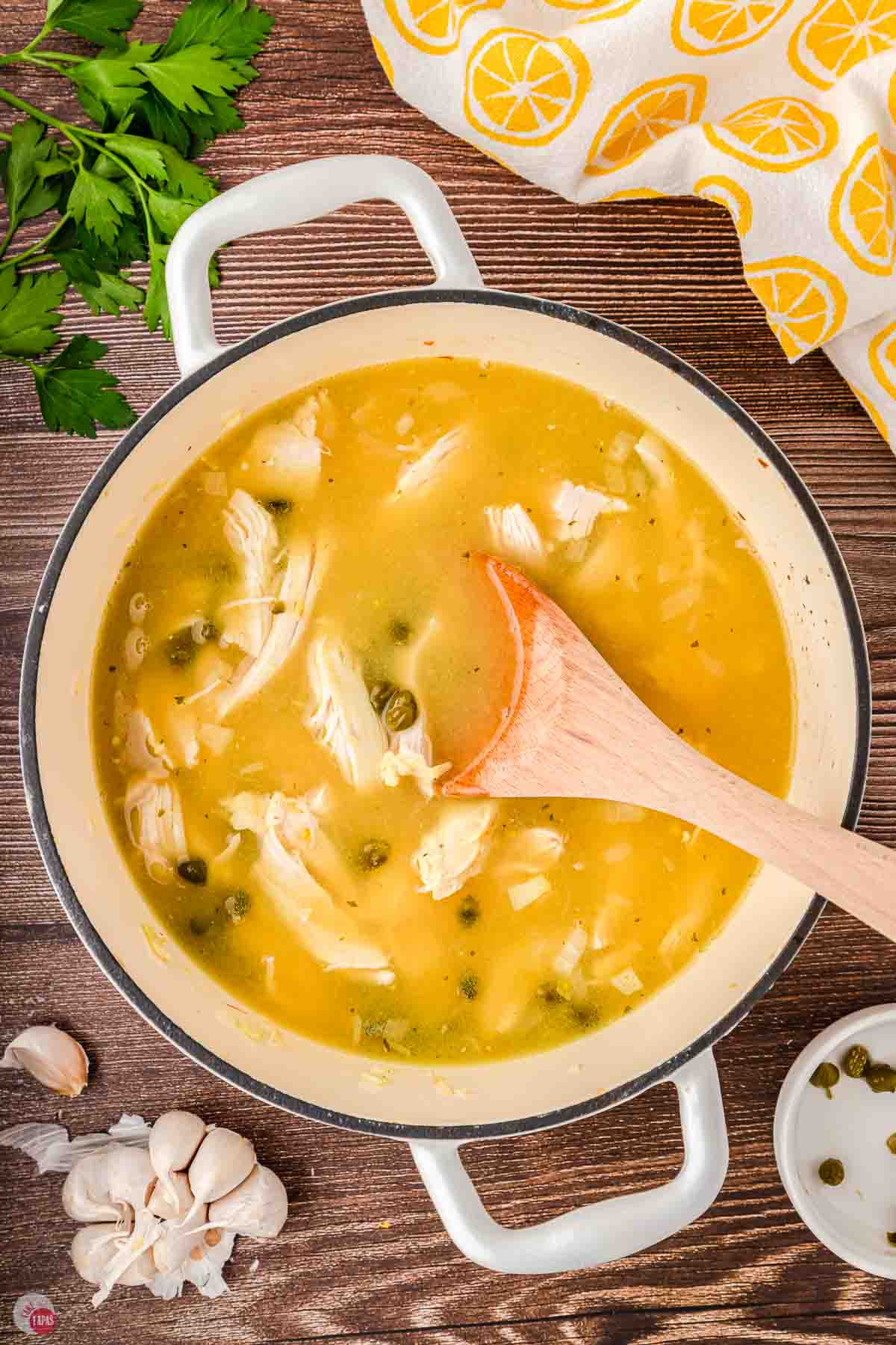 white pot with wood spoon stirring chicken soup
