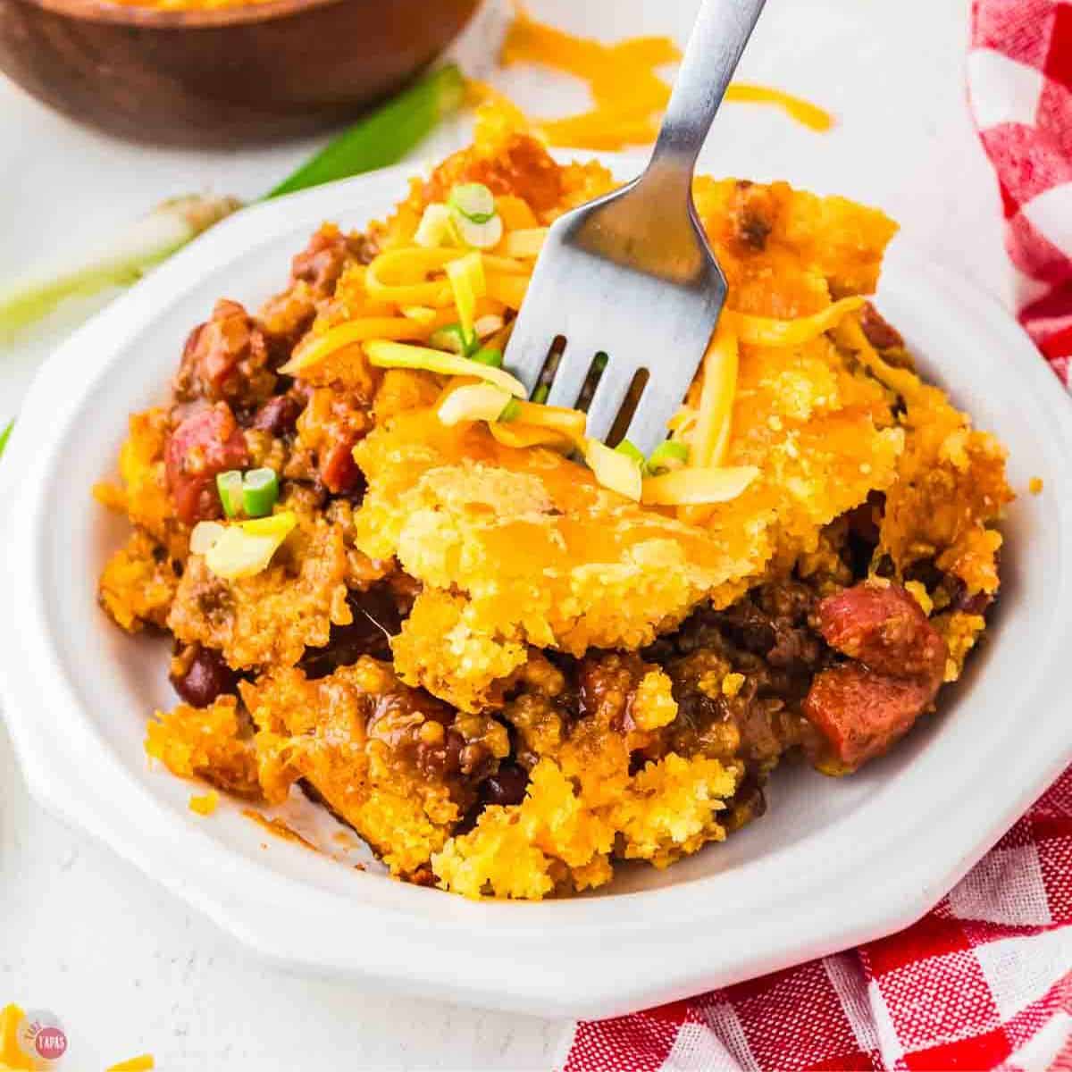 white plate with slice of chili dog casserole with a fork in it