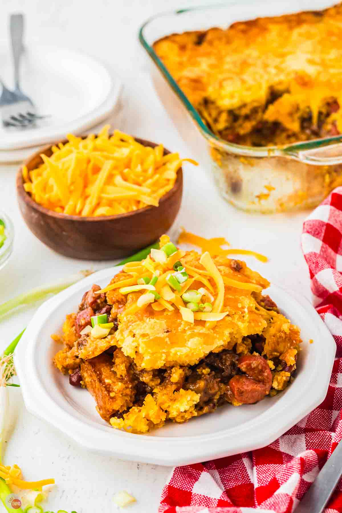 plate of casserole next to a small bowl fo shredded cheddar cheese