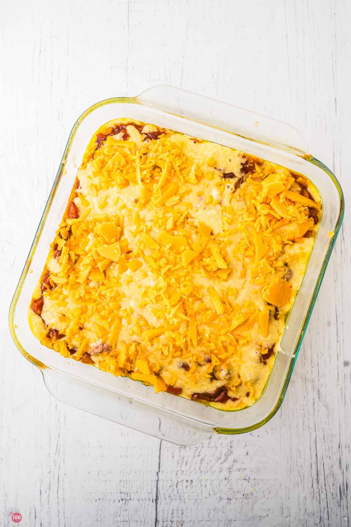 casserole dish with chil, hot dogs, and cheese unbaked