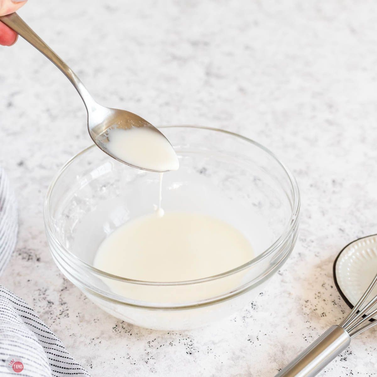 small clear bowl with a cornstarch slurry and a spoon