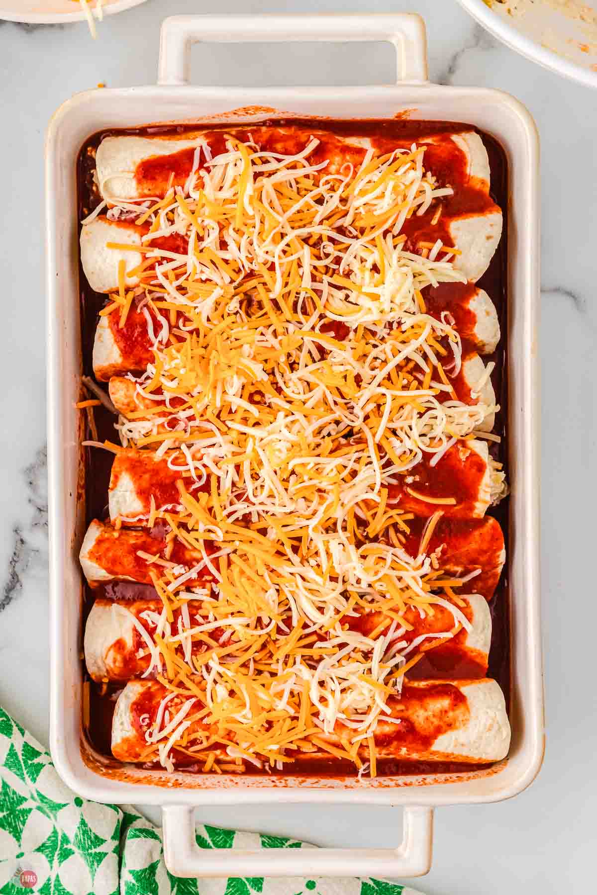 unbaked cream cheese chicken enchiladas in a white casserole dish