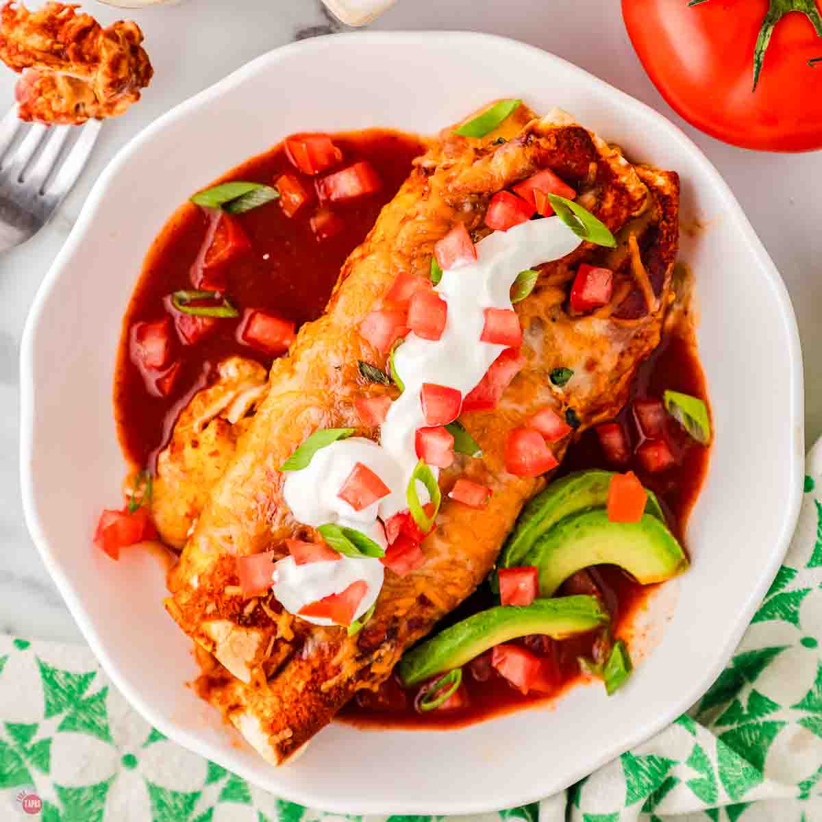 overhead picture of enchilada and sliced avocado in a shallow bowl