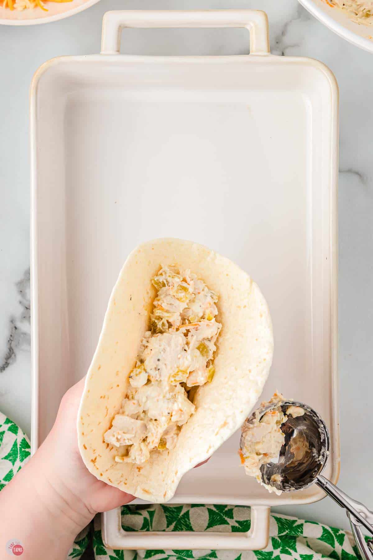 chicken mixture being spooned into a flour tortilla