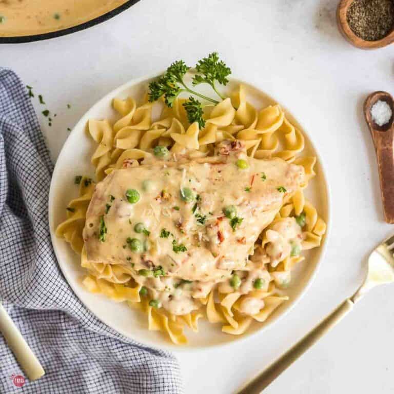 creamy garlic sauce and chicken on top of plate of egg noodles