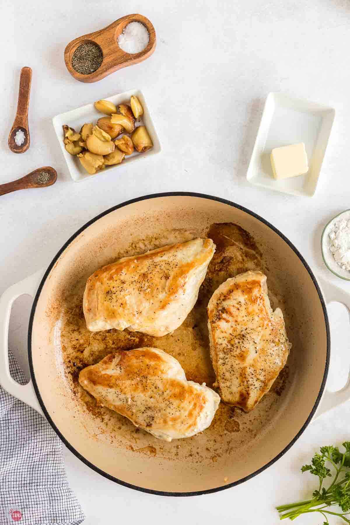 chicken breasts being seared in a white pan