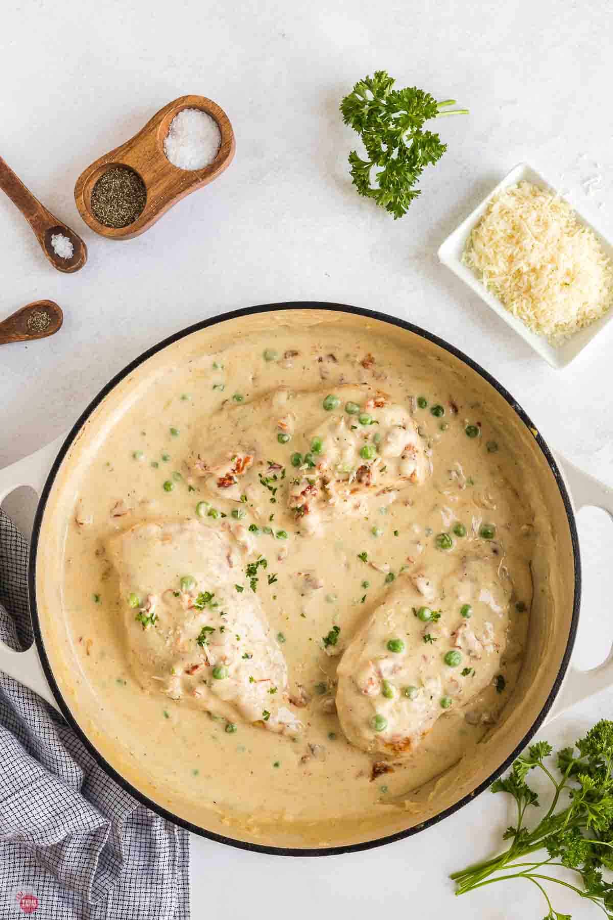 white skillet with chicken and a creamy sauce