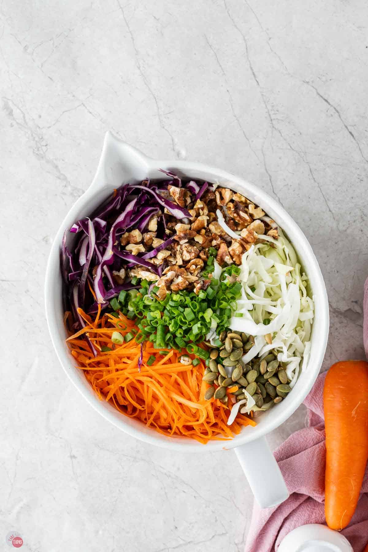 ingredients for coleslaw in a white bowl, unmixed
