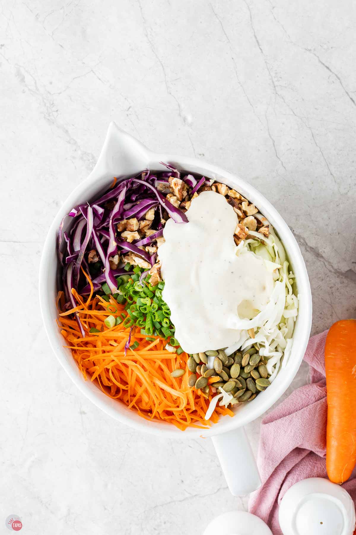 coleslaw mix in a white bowl with a dollop of dressing on top