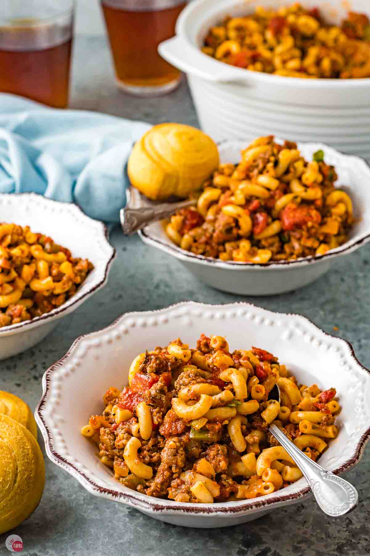 three bowls of goulash on a table with a blue napkin