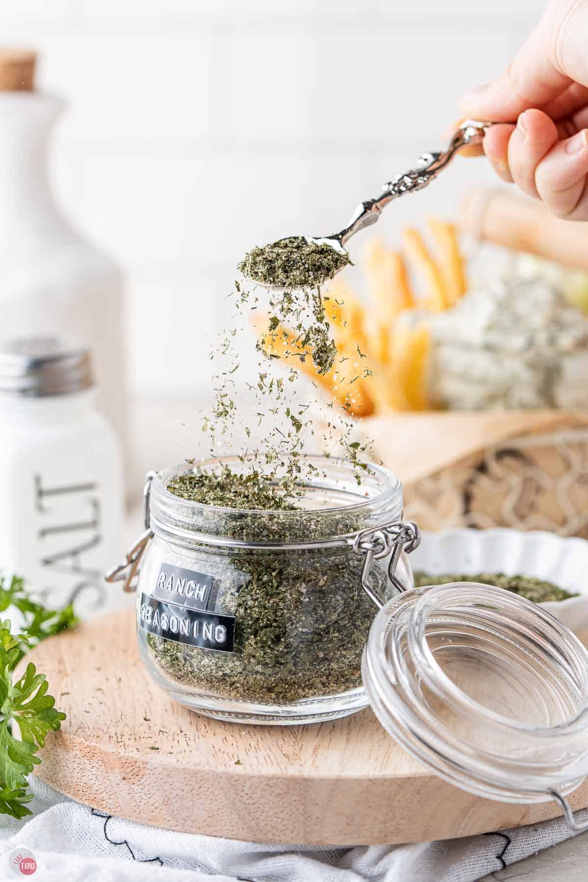 jar of ranch seasoning with a spoon scooping some out and sprinkling it back in