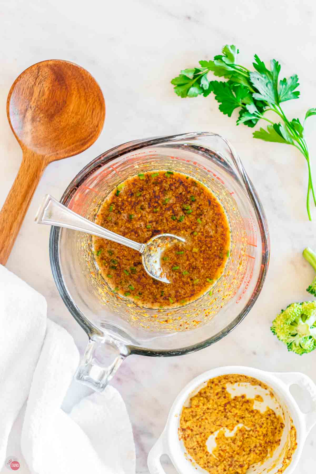 glass measuring cup with a spoon and honey mustard dressing