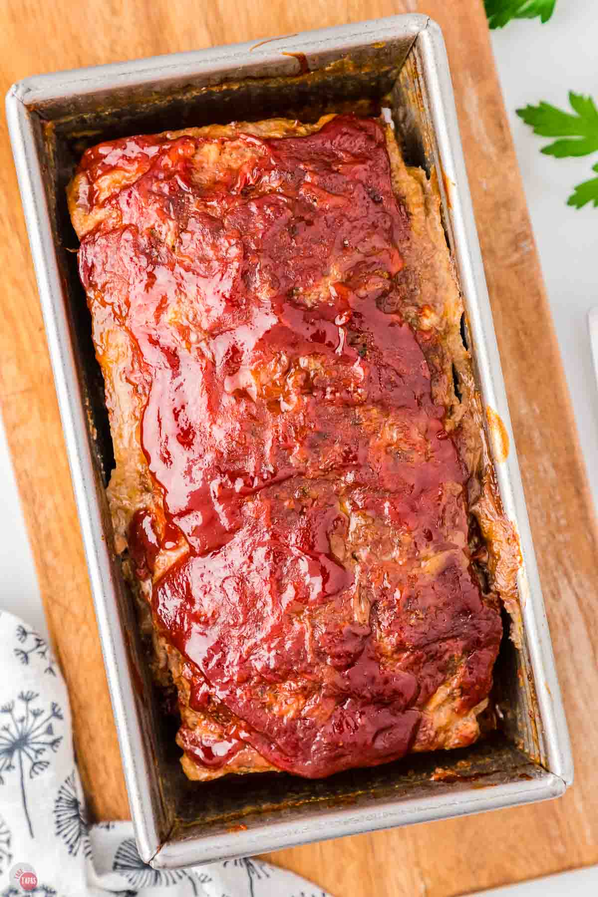 baked meatloaf in a loaf pan sitting on a wood board