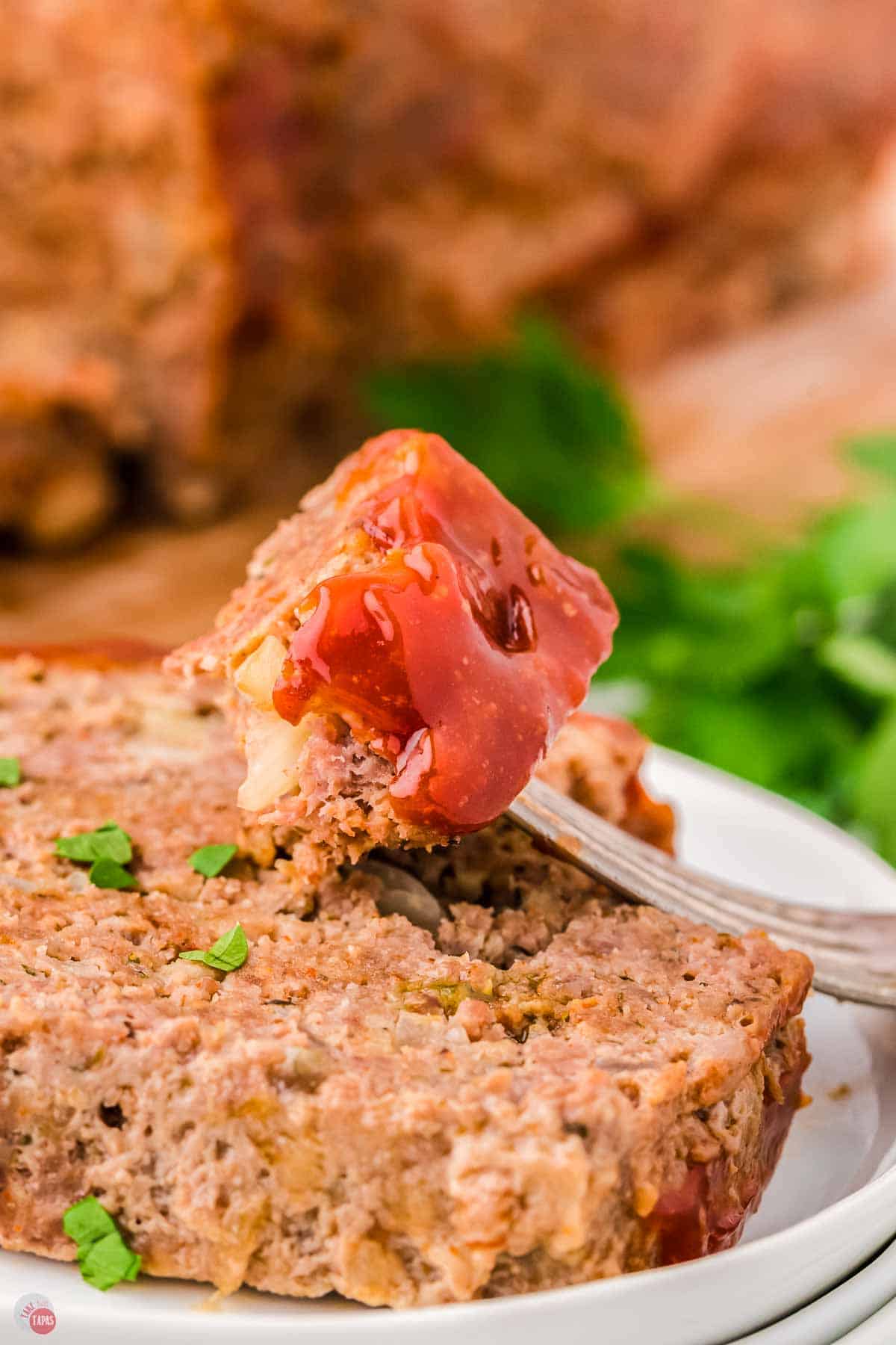 fork with bite of meatloaf resting on a slice