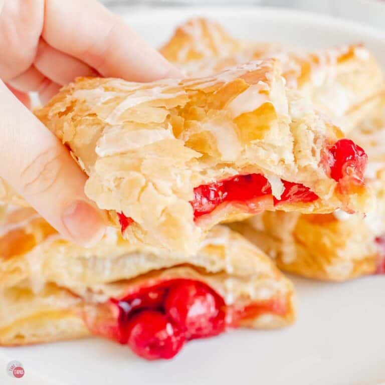 hand holding a cherry turnover with a bite missing