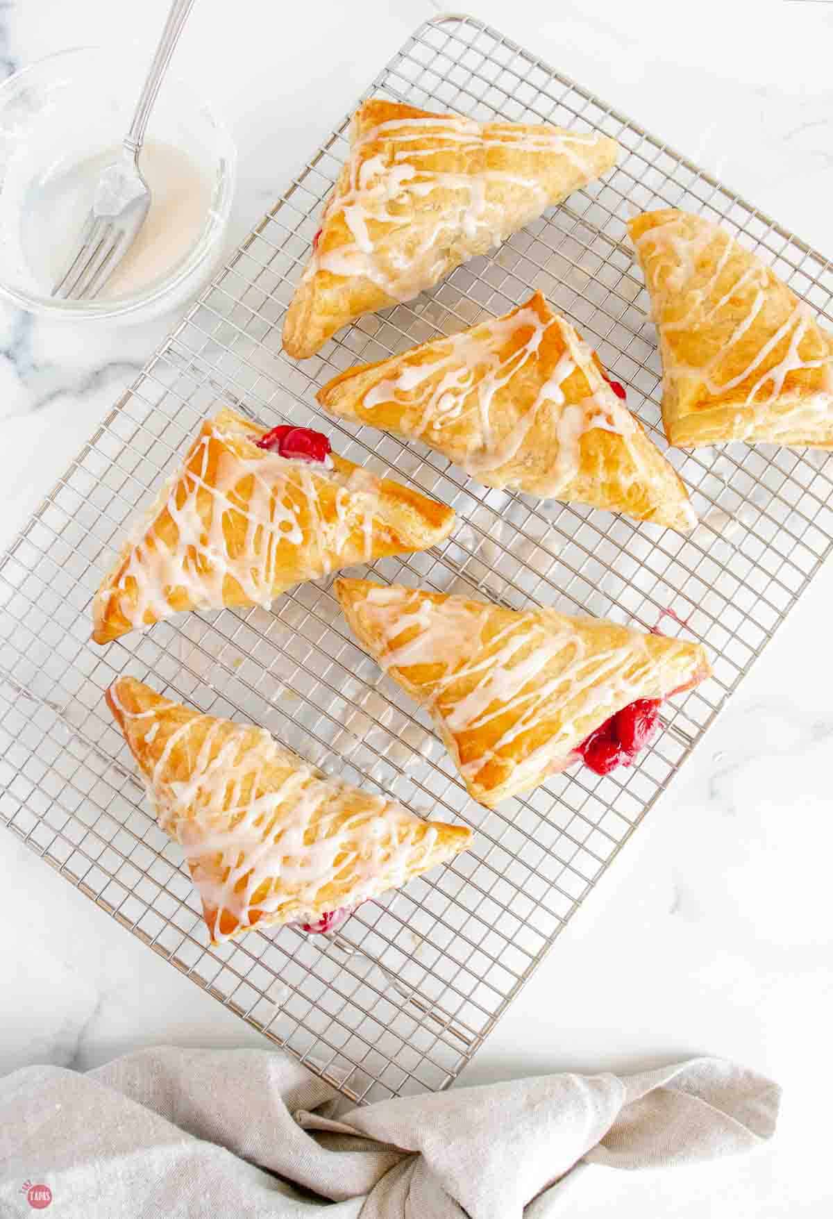 overhead picture of cooling rack topped with 6 puff pastry cherry turnovers